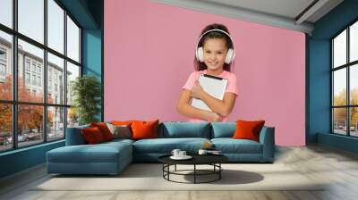 pretty little child girl in headphones using digital tablet on pink background Wall mural