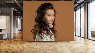 profile of cute smiling little child girl in white sweater looking to camera on beige background. Human emotions and facial expression Wall mural