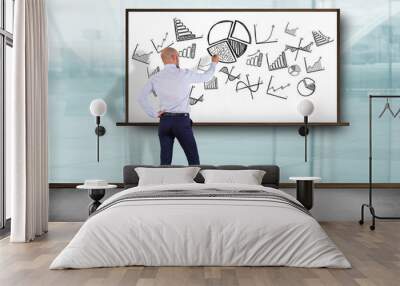 Businessman in front of a wall writing on hand drawn business interface - business concept Wall mural