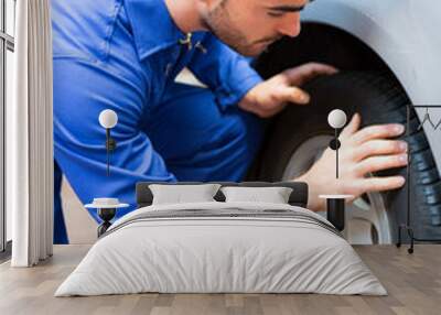 Young attractive mechanic working on a car at the garage Wall mural