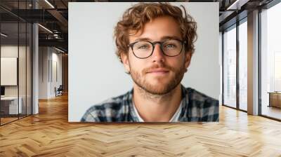 a man with glasses and a beard looks at the camera with a smile on his face and a plaid shirt.. Wall mural