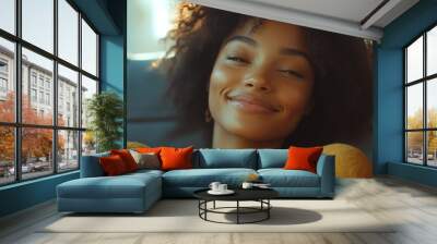 A woman with curly hair is smiling and looking at the camera Wall mural