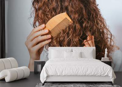 Close-up young woman combing her curly hair Wall mural