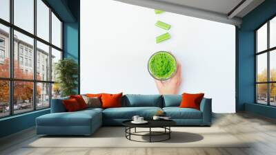 Female hand holds glass of green smoothie drink Wall mural