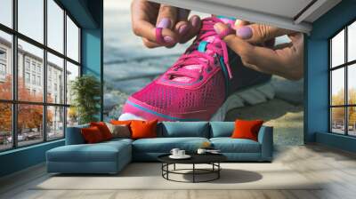 Hands of a young woman lacing sneakers Wall mural