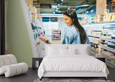 Happy young woman shopping for alcohol drinks Wall mural