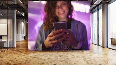 Happy young woman standing on festively lit purple neon signs city street Wall mural