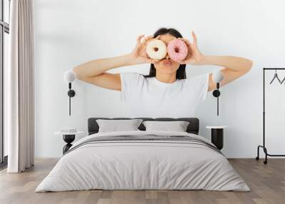 Portrait funny young woman posing with two donuts as glasses Wall mural