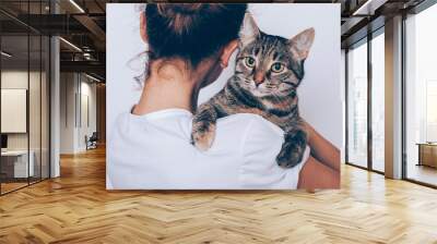 Unrecognizable young woman holding her striped cat Wall mural