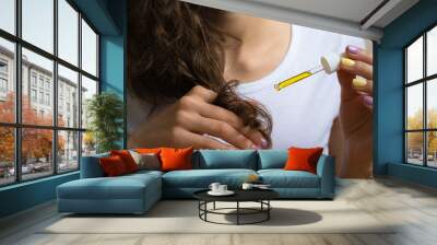 Young girl caring for curly hair tips using a  oil Wall mural