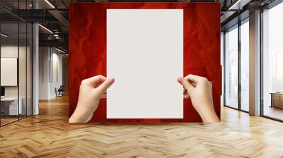 Hands holding a white paper blank isolated on red background Wall mural