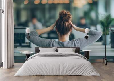 A young woman takes a moment to relax at her desk in a busy office environment during a typical workday Wall mural