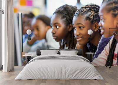 A group of young African American girls smile while looking at a computer screen at school. Wall mural