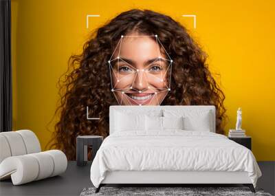 A woman with curly hair smiles brightly as a facial recognition overlay appears on her face against a vibrant yellow background. Wall mural