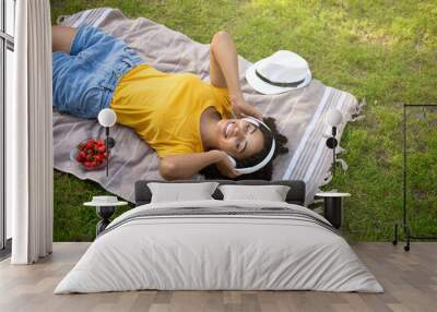 Above view of African American woman with headphones listening to music during picnic at park Wall mural