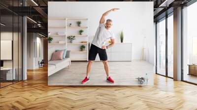 Active lifestyle. Mature man doing flexibility exercises for healthier living, working out at home, empty space Wall mural