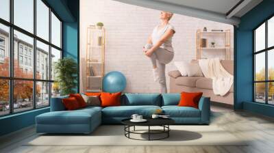 Active senior woman doing legs exercise at home Wall mural