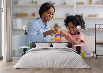 Adorable black kid and child development specialist playing with bricks Wall mural