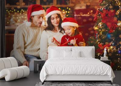 Adorable little girl openng xmas gifts with mom and dad Wall mural