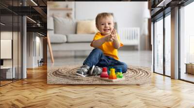 adorable toddler boy playing with educational wooden toy at home, clapping hands and smiling, sittin Wall mural