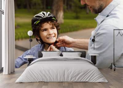 Adult man putting safety helmet on his son Wall mural