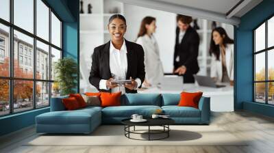 African american CEO businesswoman posing with digital tablet in front of her colleagues working on background Wall mural