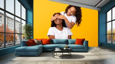 African American daughter covering her mother's eyes at studio Wall mural