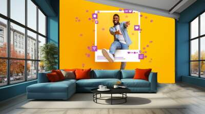 African American guy dancing and jumping out of photo frame on yellow background, collage with social media reactions Wall mural