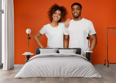 African american man and woman smiling on orange background Wall mural