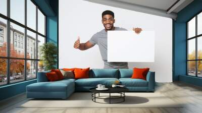 African-american man holding white blank board and showing thumb up Wall mural