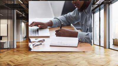 African American worker noting information from laptop in office Wall mural