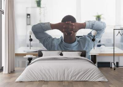 African american worker resting at workplace, leaning back on chair Wall mural