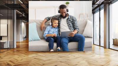 African Father And Kid Wearing Headphones Using Tablet At Home Wall mural