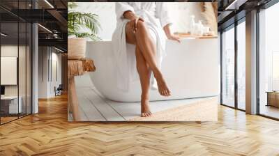 african female touching legs sitting on bathtub in bathroom, cropped Wall mural