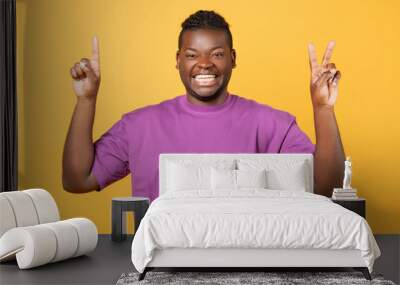 African guy raising hands showing one and two fingers, studio Wall mural