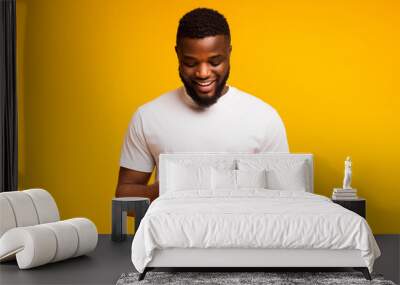 African man playing video game on mobile phone and smiling Wall mural