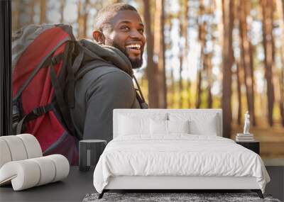 African man wearing backpack standing on forest trail Wall mural