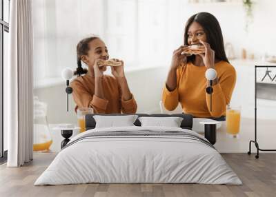 African Mom And Daughter Eating Sandwiches Having Lunch In Kitchen Wall mural