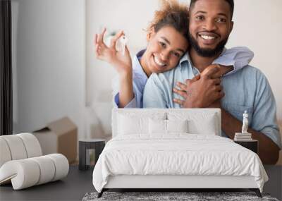 Afro Spouses Showing Key To Camera Embracing In New Home Wall mural