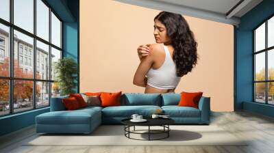 Annoyed young indian woman scratching her irritated body skin Wall mural