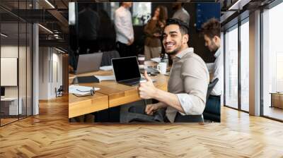 Arab businesman sitting at desk showing thumbs up gesture Wall mural