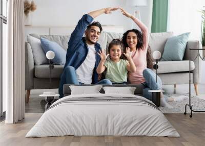 Arabic parents making symbolic roof of hands above their cute little daughter Wall mural