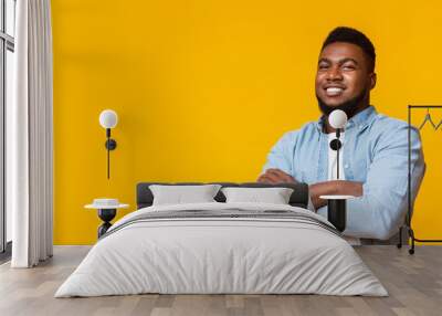 Attractive black guy with folded arms over yellow background Wall mural