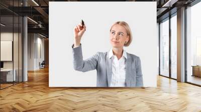 Attractive business lady writing or drawing on virtual screen against light background, space for design Wall mural