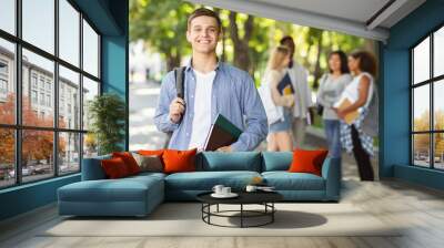 Attractive young guy student spending time with friends after university Wall mural