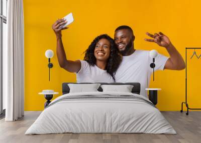 Beautiful afro couple taking selfie on smartphone Wall mural