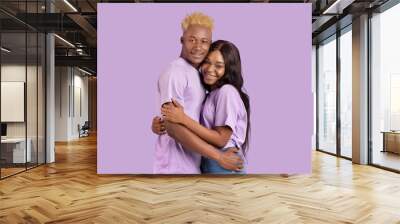 Beautiful black couple feeling in love, embracing and feeling happy over violet studio background Wall mural