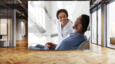 Beautiful black lady dentist greeting male patient on her workplace Wall mural