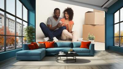 Black couple sitting on floor at new apartment Wall mural