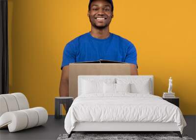 Black delivery man holding cardboard box showing it to camera Wall mural